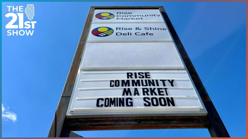 a tall store sign against a clear blue sky; it reads Rise Community Market and Rise & Shine Deli Cafe, with movable type at the bottom reading 