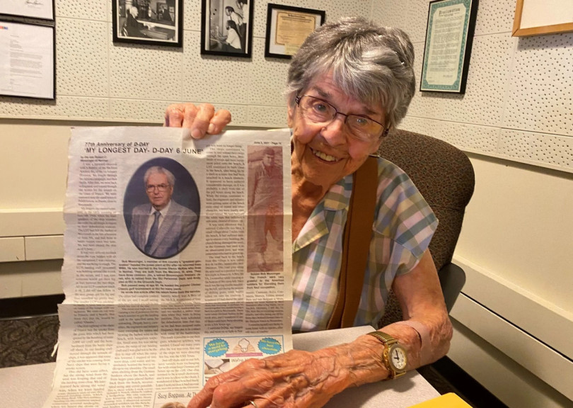 Eleanor Monninger holds up a Normalite newspaper article in which her now late husband wrote about his experience serving during the D-Day invasion.