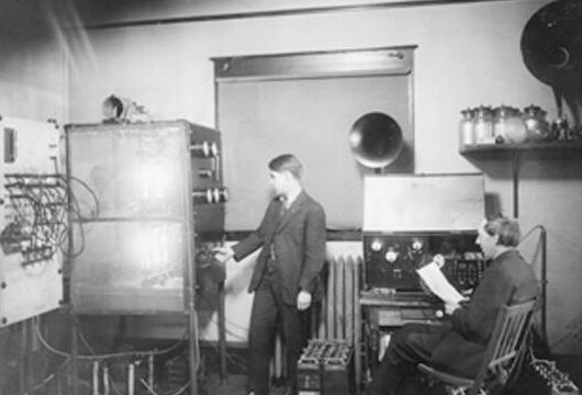 Two men working in room with transmitter and vacuum tubes