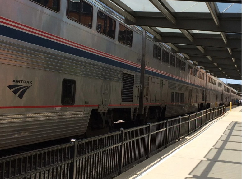 A grey Amtrak train waits at a station 