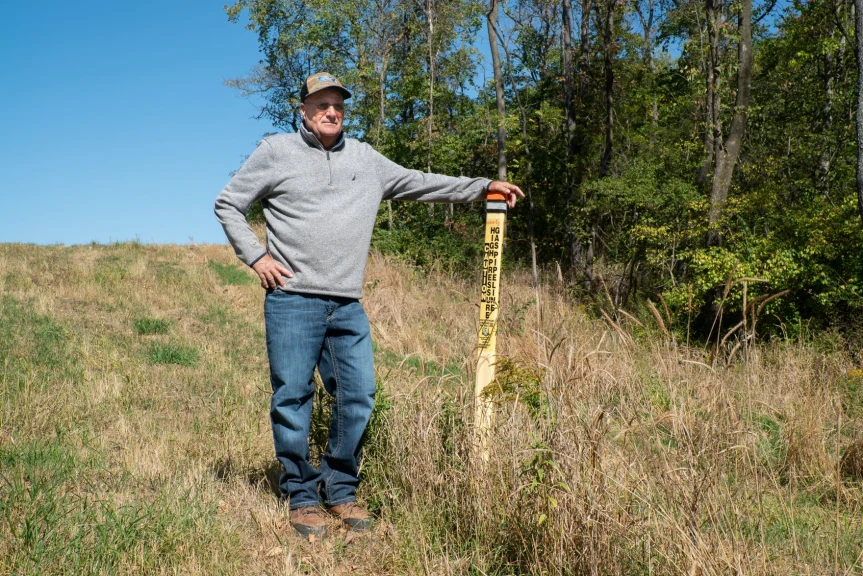 Kenny Davis stands next to the yellow tag marking where a natural gas pipeline traverses underneath his Scott County, Illinois farm on Oct. 9, 2023.