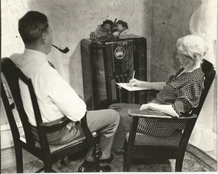 man and woman sit around radio in 1930s