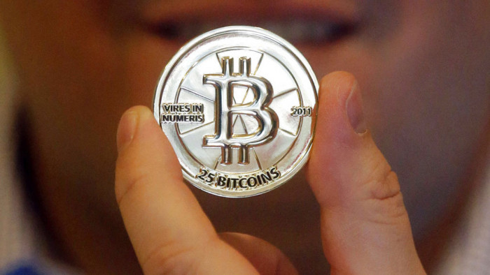 Mike Caldwell, a software engineer, holds a 25 Bitcoin token at his shop in Sandy, Utah. Bitcoin is an online currency that allows people to make one-to-one transactions, buy goods and services and exchange money across borders without involving banks, credit card issuers or other third parties.