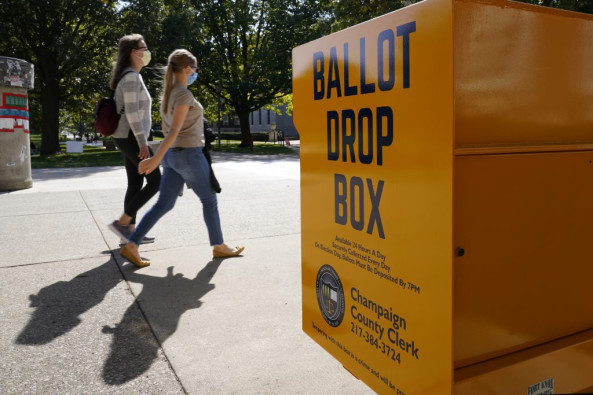 University of Illinois students Tuesday, Oct. 6, 2020, walk past a mail-in ballot drop box that sits on the northwest corner of the university's Quad in Urbana.