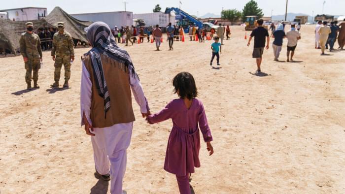 A man walks with a child through Fort Bliss' Doña Ana Village where Afghan refugees are being housed, in New Mexico, Friday, Sept. 10, 2021. The Biden administration provided the first public look inside the U.S. military base where Afghans airlifted out of Afghanistan are screened, amid questions about how the government is caring for the refugees and vetting them. 