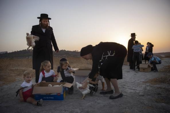  An Ultra-Orthodox Jewish man swings a chicken over his kids as part of the Kaparot ritual in Beit Shemesh, Israel, Monday, Sept. 13, 2021. Observant Jews believe the ritual transfers one's sins from the past year into the chicken, and is performed before the Day of Atonement, Yom Kippur, the holiest day in the Jewish year which starts at sundown Wednesday.