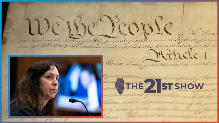 the US constitution is written on dark brown paper in elaborate script; the inset photo features a white woman with brown hair and wearing a black top; she's looking to her right and her lips are pursed; on a TV monitor in the background — out of focus — you can see a senator holding up a piece of paper, presumably asking a question or making a point during Shogan's confirmation hearing