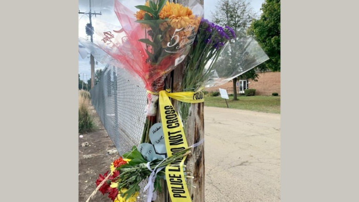 Flowers are taped to a utility pole by police tape near the place a 17-year-old Champaign student was fatally shot in September  2021.