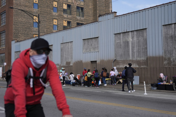 People hang around outside of a migrant shelter Wednesday, March 13, 2024, in the Pilsen neighborhood of Chicago. Multiple people living at the shelter for migrants have tested positive for measles since last week. A team from the Centers for Disease Control and Prevention is supporting local officials' response. 