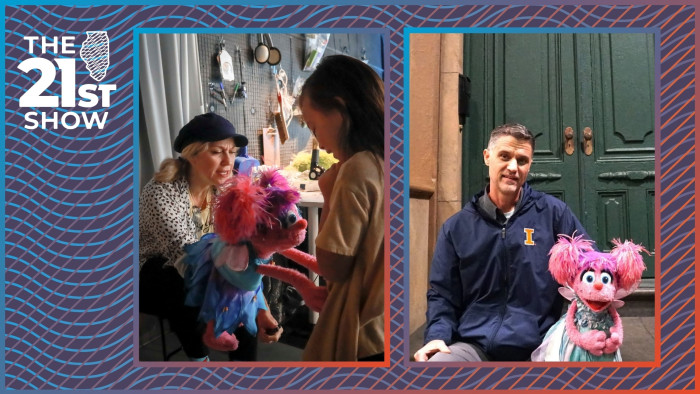 a woman in a white shirt with heart-shaped polka dots holds a pink puppet with a blue dress talking to a young girl wearing a beige t-shirt; a man in a navy windblazer with the University of Illinois orange block-I logo sits in front of double green doors on an urban stoop next to a pink puppet wearing a teal dress