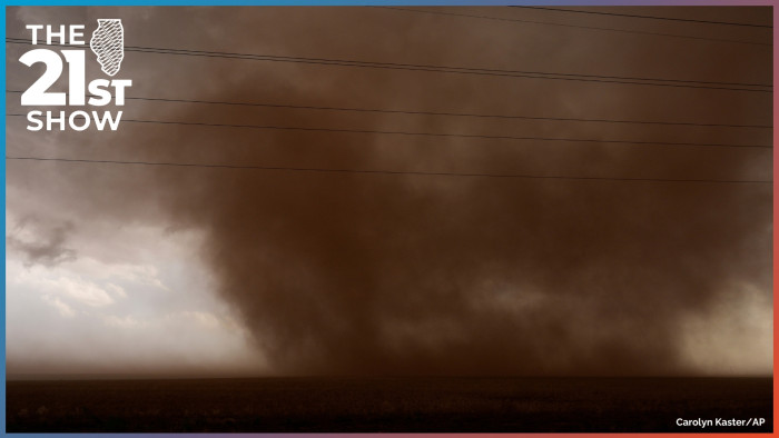 the brown dust of a whirling tornado fills most of the frame and darkens the skies