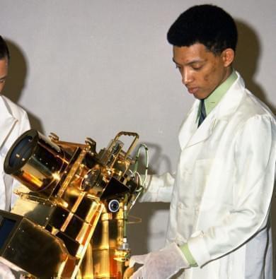 Dr. George Carruthers, a scientist at the Naval Research Laboratory, stands to the right of his invention, the gold-plated ultraviolet camera/spectrograph. The first Moon-based observatory, Carruthers developed it for the Apollo 16 mission. 