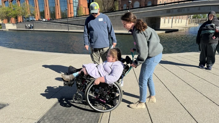 Occupational therapist and Skills on Wheels volunteer Maria Fuchs guides 12-year-old Savannah Healton through some wheelchair skills. Savannah's parents, Matthew White and Chanda Healton, observe and learn to be able to help her as she practices.