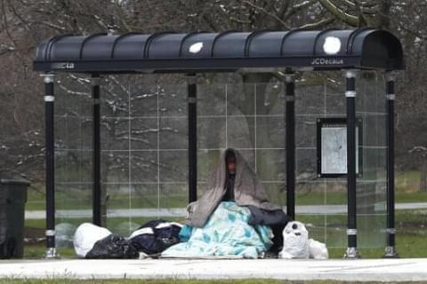 A homeless man occupies a Chicago Transit Authority bus shelter during the coronavirus pandemic on the city's West Side Wednesday, April 15, 2020.