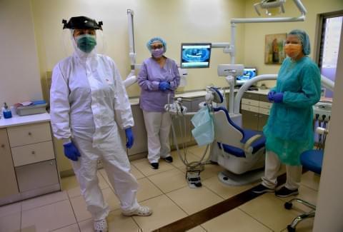 Greek dentist Dimitra Karaiskou, left, wearing a full protective suit against the coronavirus, along with her assistants Maria Vrettou, center, and Sofia Vasilaki, right, also wearing protective equipment, pose for a photo during the first day of the re-opening of their dental clinic, following a lockdown to stop the spread of the coronavirus, in this file photo from May 4, 2020.