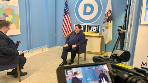 Brian Mackey, host of The 21st, interviewing Gov. JB Pritzker (D-IL) in 2022.