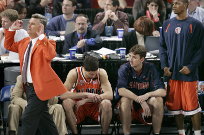 Former Illinois coach Bruce Weber in front of basketball players sitting on a bench. 