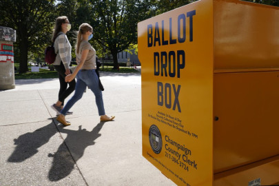 University of Illinois students Tuesday, Oct. 6, 2020, walk past a mail-in ballot drop box that sits on the northwest corner of the university's Quad in Urbana.