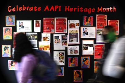 In this Monday, May 10, 2021 students walk past a display for Asian Pacific American Heritage Month at Farmington High School in Farmington, Conn.