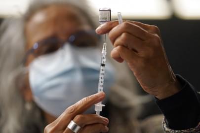 Dr. Manjul Shukla transfers Pfizer COVID-19 vaccine into a syringe, Thursday, Dec. 2, 2021, at a mobile vaccination clinic in Worcester, Mass. 