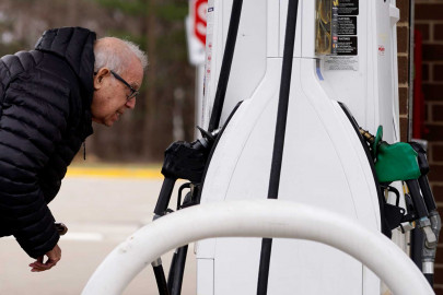 A man checks gas prices at a gas station in Buffalo Grove, Ill., Saturday, March 26, 2022. A University of Illinois professor says the Russian invasion of Ukraine is just one factor in high prices at the pump.