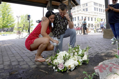 Brooke and Matt Strauss, who were married Sunday, pause after leaving their wedding bouquets in downtown Highland Park, Ill., a Chicago suburb, near the scene of Monday's mass shooting, Tuesday, July 5, 2022.