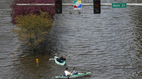Kayakers float down a flooded street, Monday, May 1, 2023, in downtown Davenport, Iowa. The rising Mississippi River is testing flood defenses in southeast Iowa and northwest Illinois as it nears forecast crests in the area Monday, driven by a spring surge of water from melting snow.