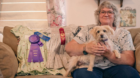 woman sits on a couch with ribbons dresses and dog