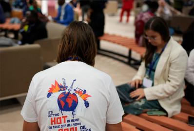 An attendee wears a shirt protesting coal, oil and gas at the COP28 U.N. Climate Summit, Thursday, Nov. 30, 2023, in Dubai, United Arab Emirates.