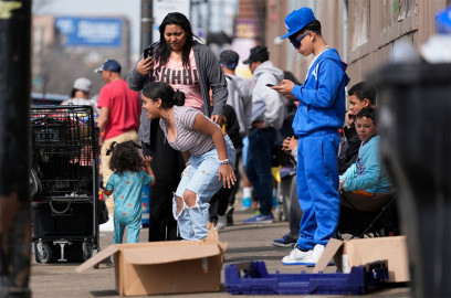 People hang around outside of a migrant shelter Wednesday, March 13, 2024, in the Pilsen neighborhood of Chicago. On Friday, Mayor Brandon Johnson's administration announced it will proceed with evicting those who have been in a shelter for 60 days except for migrant families with children and those who've been affected by a measles outbreak.