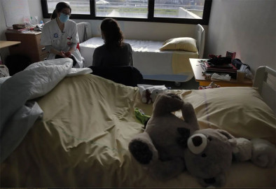 In a file photo from March 2, 2021, psychiatrist Coline Stordeur speaks with a young girl in her room in the pediatric unite of the Robert Debre hospital.