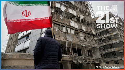 A man holds an Iranian flag as he looks at the damaged façade of Gandhi Hospital, which was hit Sunday when a strike also struck a state TV communications tower and nearby buildings across the street during the ongoing joint U.S.–Israeli military campaign in Tehran, Iran, Monday, March 2, 2026.