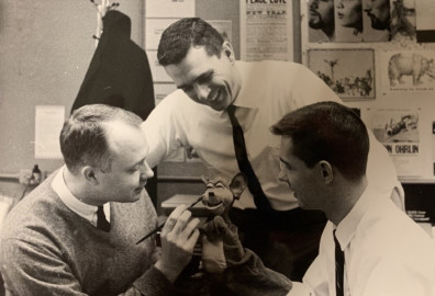 three men stand around hand puppet painting final touches