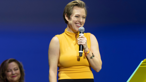woman in yellow tank top holding a microphone on stage