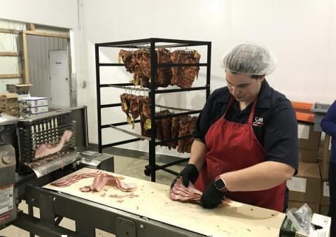 A worker at Swiss Meat and Sausage prepares bacon for sale in this 2019 file photo.