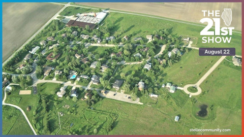 several dozen homes fill a small subdivision filled with trees and surrounded by green fields