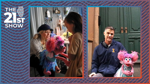 a woman in a white shirt with heart-shaped polka dots holds a pink puppet with a blue dress talking to a young girl wearing a beige t-shirt; a man in a navy windblazer with the University of Illinois orange block-I logo sits in front of double green doors on an urban stoop next to a pink puppet wearing a teal dress