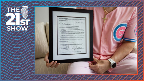 a man in a pink Chicago Cubs jersey cradles a framed legal document