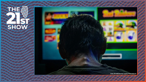 a man with short hair is silhouetted against the glow of video gambling machines
