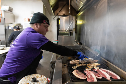Chef Jesus Finol prepares a steak arepa at Sabe a Zulia, a Venezuelan restaurant in Chicago. Restaurant co-owner Gerardo Abreu volunteered to help feed the first groups of migrants arriving in the city in 2022. He says they figured out how to cook food that migrants want to eat on a budget, but the city has had some challenges doing the same in its shelters.
