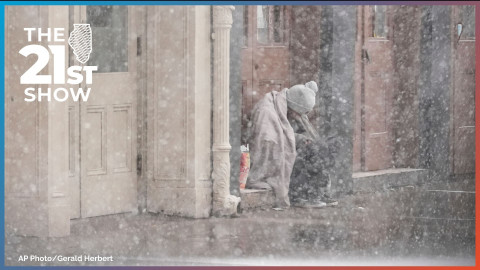 A homeless man sits in a doorway as snow falls in this file photo from January 2025.