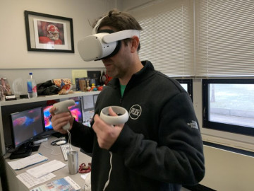 NIU professor Zach Wahl-Alexander using a Meta Quest VR headset in his office. He's using the headsets as part of instruction in his classroom.