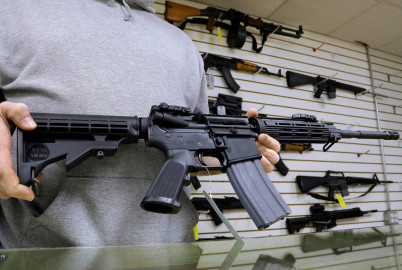 In this 2013 file photo, John Jackson, co-owner of Capitol City Arms Supply, shows off an AR-15 assault rifle for sale at his business in Springfield, Ill. Under a new state law, such weapons are banned unless their owners register the weapons with the Illinois State Police. A WBEZ analysis shows that the lowest registration rates are found in rural downstate counties.