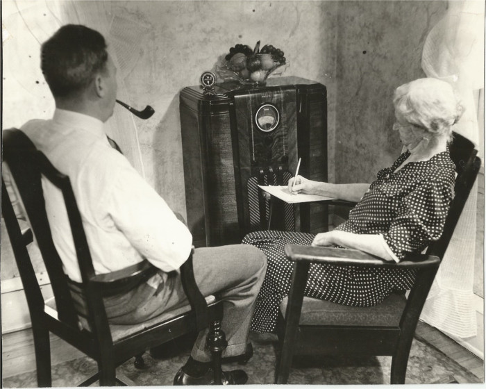 man and woman sit around radio in 1930s