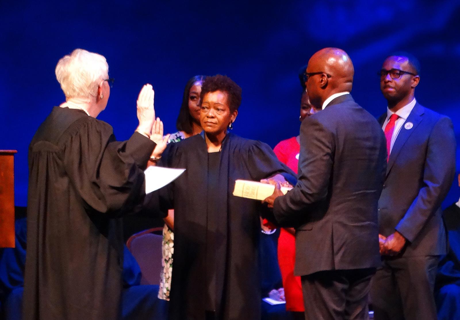 Justice Mary Jane Theis, left, administers the oath of office to Lisa Holder White, making her the first Black woman to serve on the Illinois Supreme Court. Holder White's husband James White holds a Bible while their son Brett White looks on.