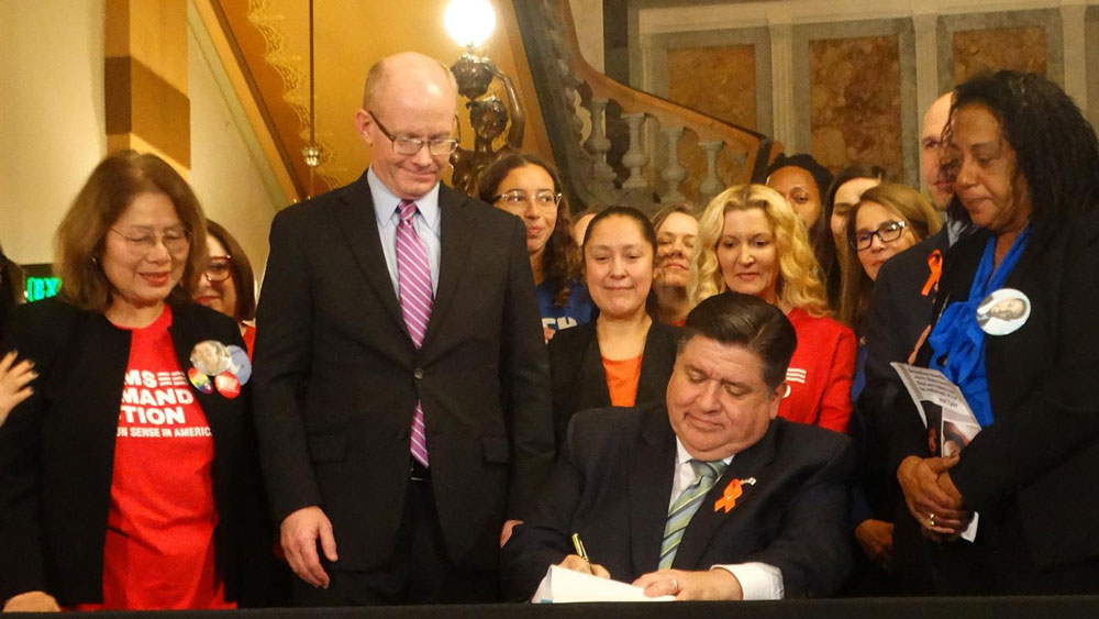 Gov. JB Pritzker signs a bill banning the sale and manufacture of assault weapons and high-capacity magazines on the Senate floor on January 10, 2023.