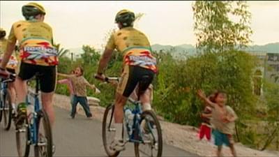 men riding bicycles past young Vietnamese children